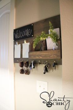 there is a sign that says welcome hanging on the wall next to keys and plants