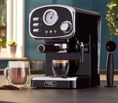 an espresso machine sitting on top of a counter next to a cup of coffee