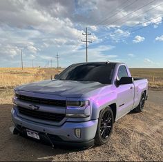 a silver truck parked on the side of a dirt road