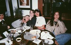 a group of people sitting around a table with food and drinks in front of them