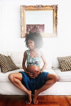 a pregnant woman sitting on top of a white couch