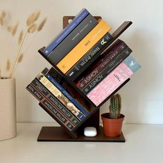 a stack of books sitting on top of a wooden stand next to a potted plant