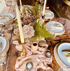 a wooden table topped with plates and candles