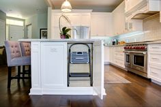 a kitchen with white cabinets and an island that has a rack on the side for cooking utensils