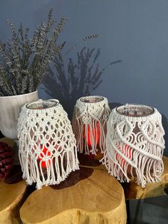 two white crocheted lamps sitting on top of a wooden table next to a potted plant