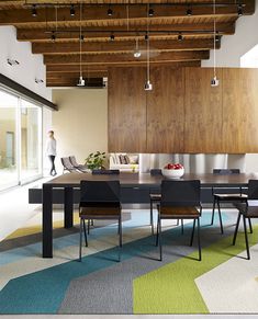 a dining room table and chairs in front of an open kitchen area with wood paneling