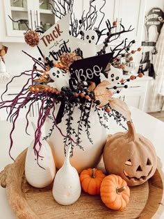 a white vase filled with halloween decorations on top of a wooden tray next to pumpkins