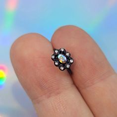 a person's hand holding a ring with a white and black flower on it