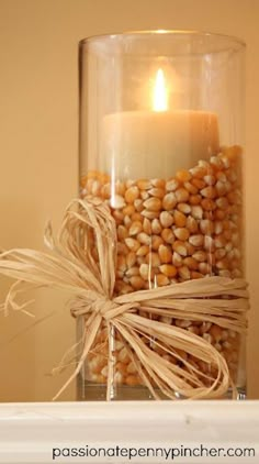 a glass jar filled with corn and a lit candle