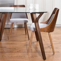 a glass table with two chairs next to it on a hard wood floor in front of a white wall