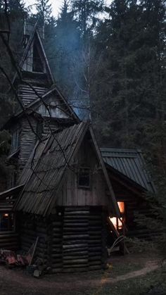 an old log cabin in the woods is lit up at night by a fire hydrant