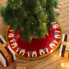 a christmas tree skirt with elephants on it and presents under the tree next to it