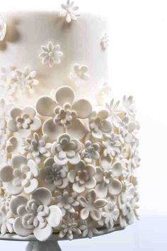 a three tiered cake with white frosting and flowers on the top is shown