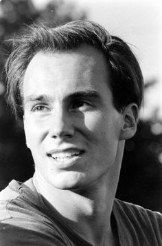 a black and white photo of a young man with short hair smiling at the camera