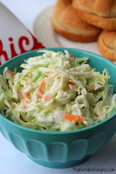 a blue bowl filled with coleslaw and carrots next to some bagels