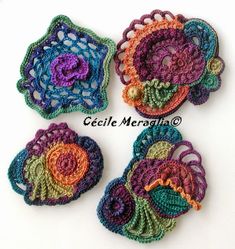 four crocheted coasters are arranged on a white surface