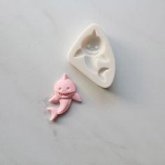 a pink plastic shark next to a white mold