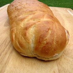 a loaf of bread sitting on top of a wooden cutting board next to a green field