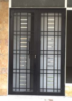 two black doors sitting next to each other in front of a building