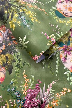 a green floral print fabric with scissors on it and flowers in the center, along with other fabrics