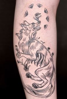 a tattoo on the leg of a woman with a deer and leaves around her legs