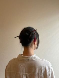 a woman standing in front of a white wall with her back turned to the camera