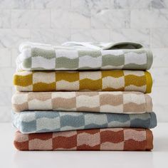 four towels stacked on top of each other in different colors and patterns, with one folded