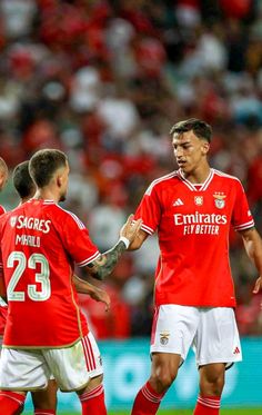 two soccer players are shaking hands with each other in front of an audience at a sporting event