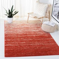 an orange rug in a white room with a chair and potted plant on the floor