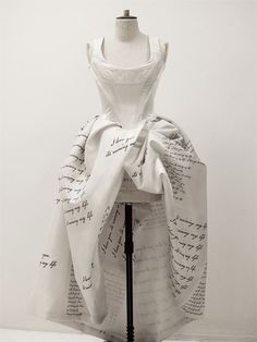 a mannequin is dressed up in a white dress with writing on the fabric