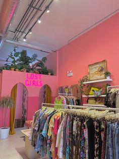 a clothing store with pink walls and clothes on racks