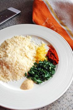 a white plate topped with different types of food on top of a table next to a cell phone