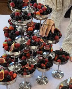 a table topped with lots of desserts and fruit on top of silver trays