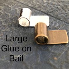 two small metal objects sitting on top of a blue surface with the words large glue on bail