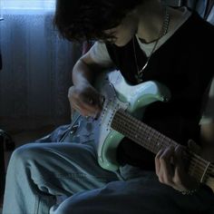 a person sitting down playing an electric guitar