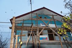 a house under construction in the middle of an area with trees and birds flying overhead