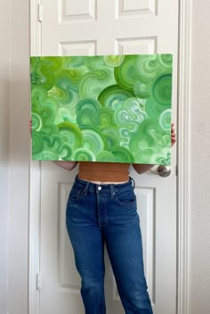 a woman holding up a painting in front of her face