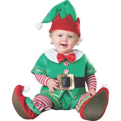 a baby dressed in an elf costume sitting on the floor with a cell phone up to its ear