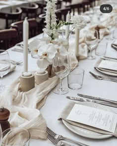 the table is set with white flowers and silverware