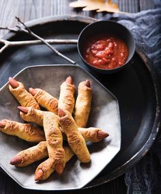 several hot dogs on a plate with dipping sauce