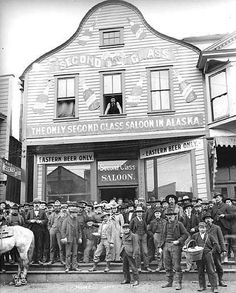 black and white photograph of men standing on steps in front of a building with signs