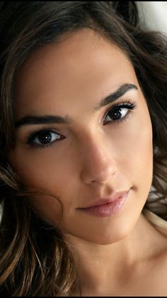 a close up of a woman with blue eyes and brown hair, looking at the camera