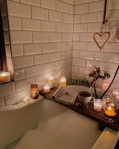 candles are lit in the corner of a bathtub next to a book and some books