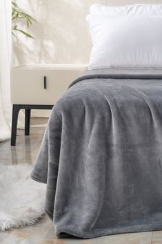 a bed with a gray blanket and white pillows