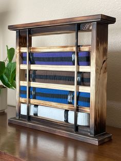 a wooden shelf holding several pairs of blue and black striped ties on top of a table