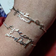 two silver bracelets on someone's arm with the word love written in cursive writing