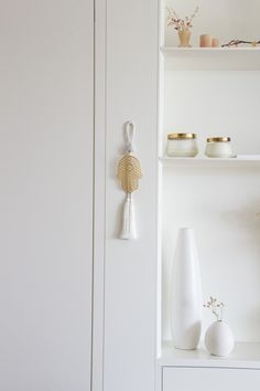 a white shelf with vases and other items on it's shelves in a room