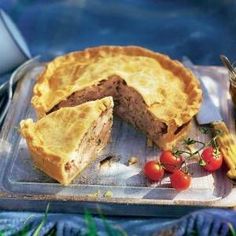 a pie with one slice cut out and cherry tomatoes on the side