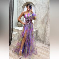 a woman taking a selfie wearing a purple dress with flowers on the side and high slit