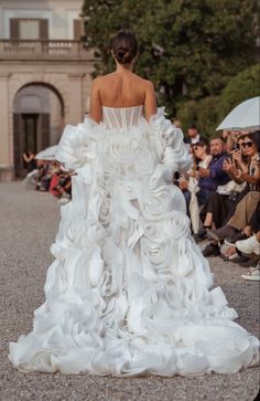 a woman in a white wedding dress is walking down the runway with her back to the camera